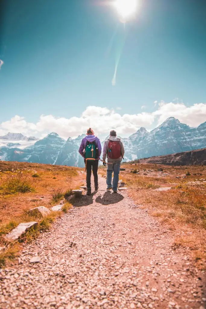 Two people hiking towards mountain peaks under a bright sky, symbolising Laura and Ian's journey to the top with Rebellion Websites