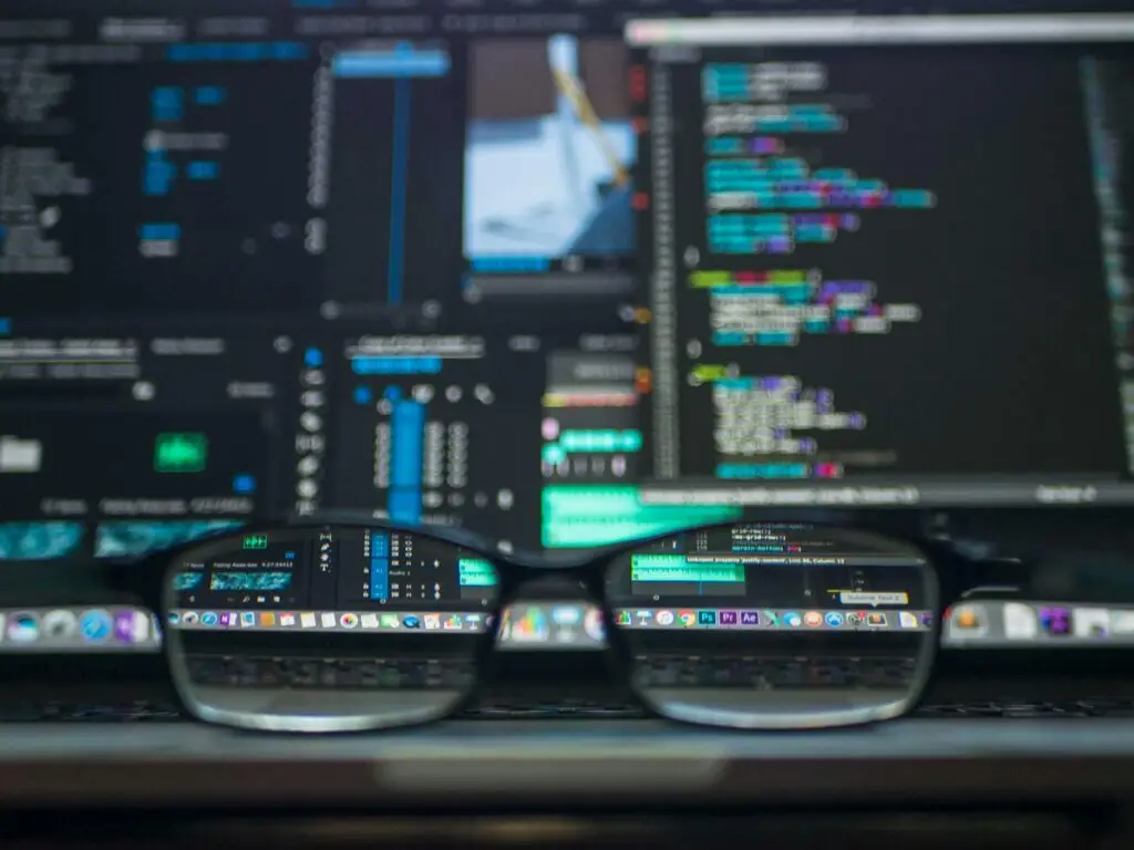 Close-up of computer code and software reflected through glasses, representing the sharp focus and technical expertise of Rebellion Websites